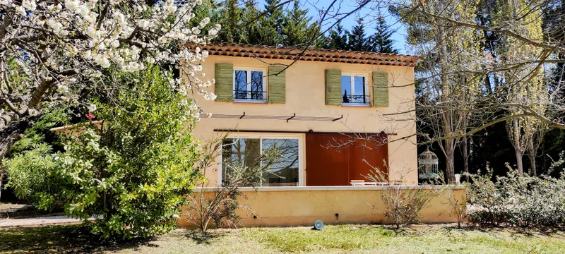 Façade du Mazet et ses volets verts derrière les branches fleuries