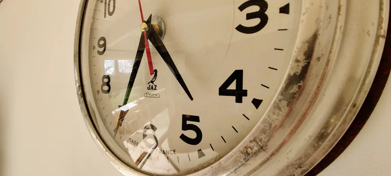 Horloge ronde à chiffres noirs sur un mur clair du cottage